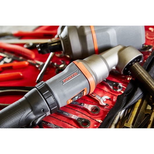 Close-up of a Proto brand ratchet tool, model J150WA, placed on top of a red tool roll containing various wrenches and pliers. The scene is well-lit, highlighting the details of the tool and the surrounding hand tools.