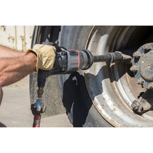 PROTO J199WP impact wrench in use tightening lug nuts on a large truck wheel outdoors.