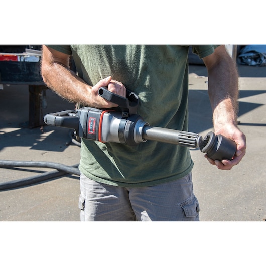 PROTO J199WP impact wrench held by person, showing tool and socket outdoors.