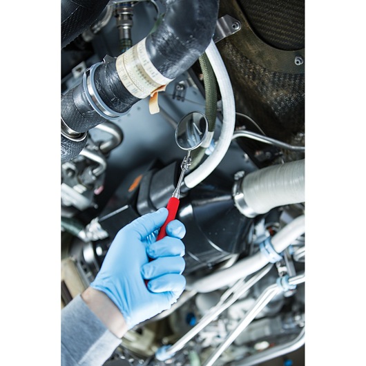 PROTO J2374 inspection mirror with red handle used to check pipes in machinery by gloved hand, close-up photo.