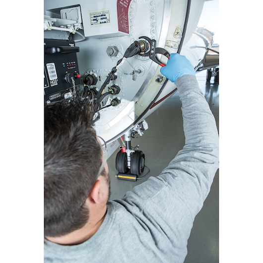PROTO J253G pliers being used by a technician on an aircraft panel, close-up view of hands and tool in action.