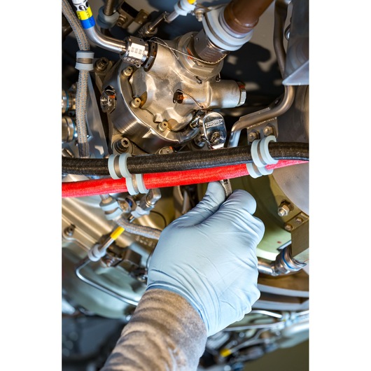 PROTO J4771TA wrench being used by a gloved hand to tighten a bolt on industrial machinery, close-up photography.