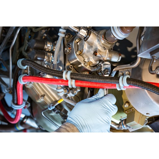 Photo of a gloved hand using a PROTO J4771TA ratchet wrench on engine components with red and black hoses.