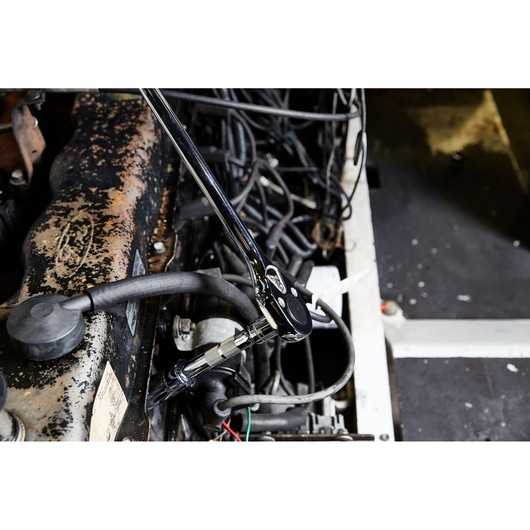 PROTO J5450 chrome ratchet wrench in use on an engine with visible hoses and wires.