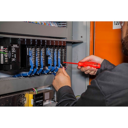 PROTO insulated screwdriver J90001-VDE used by technician working on electrical panel with blue wires, action shot.